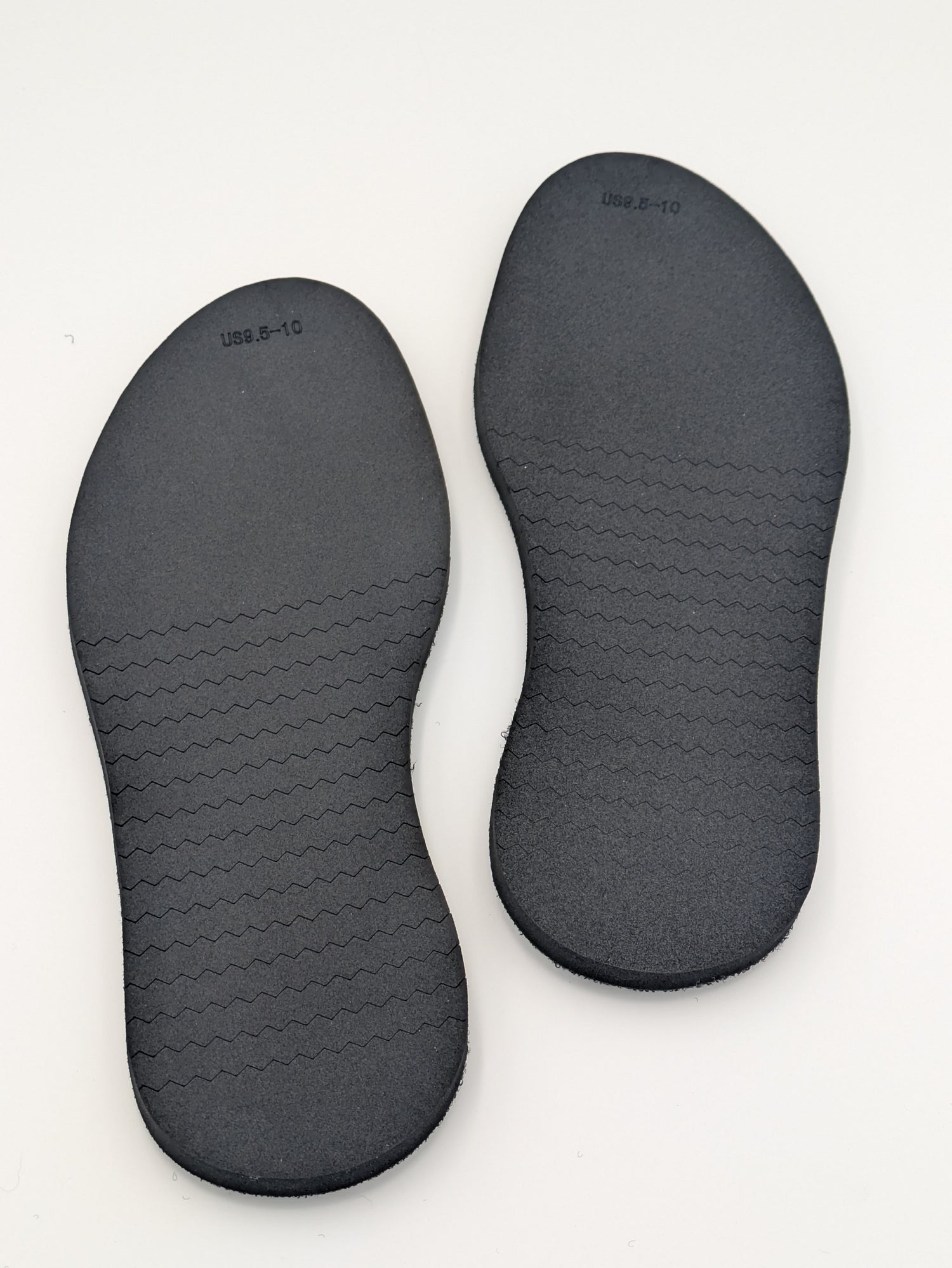 Pair of black shoe outsoles on a white background
